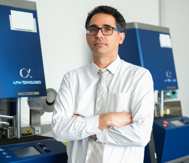 A person standing near a rheology instrument with arms crossed